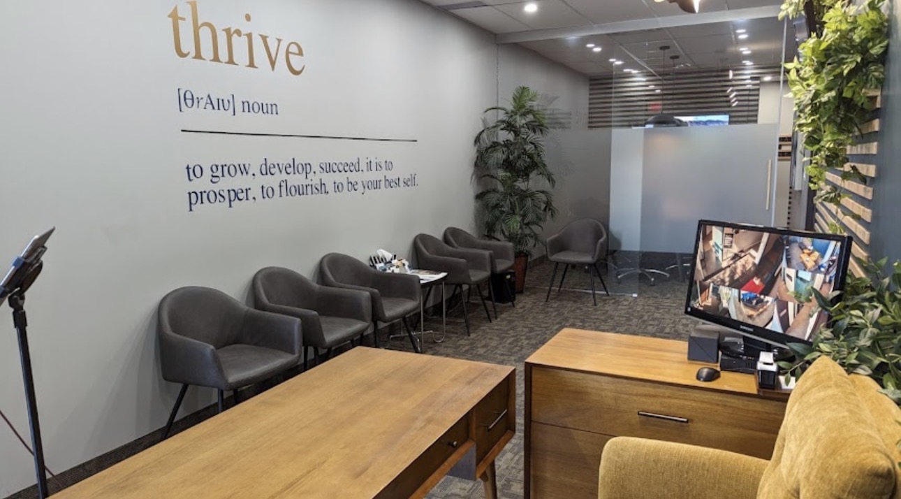 Waiting lounge with comfortable seating and a 'thrive' wall quote