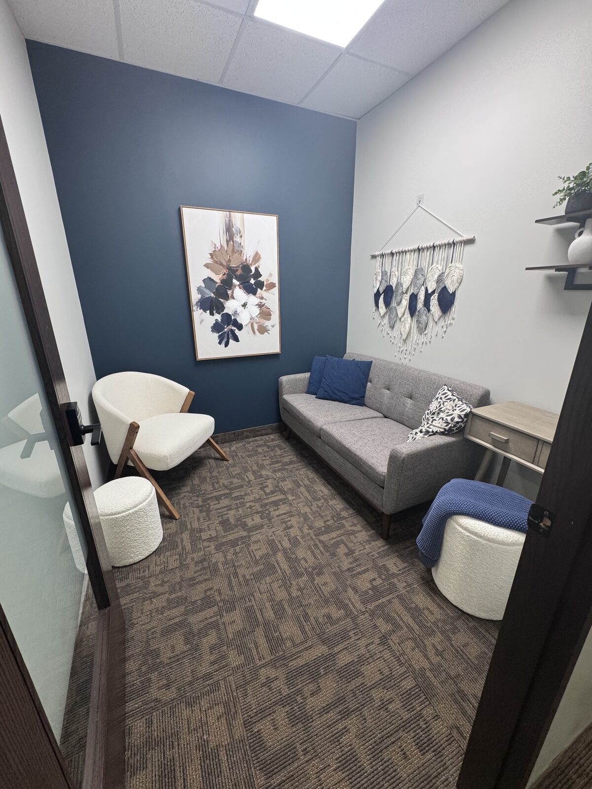 Private therapy room with a boucle chair, grey sofa and navy accent wall
